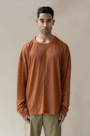 Man in oversized terracotta shirt and khaki trousers.