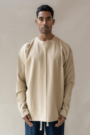 Man modeling beige crewneck sweatshirt and navy trousers.