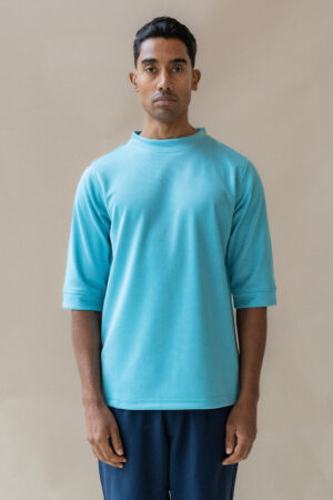 Man wearing light blue t-shirt, neutral background.