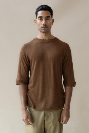 Man in brown t-shirt and beige trousers standing.